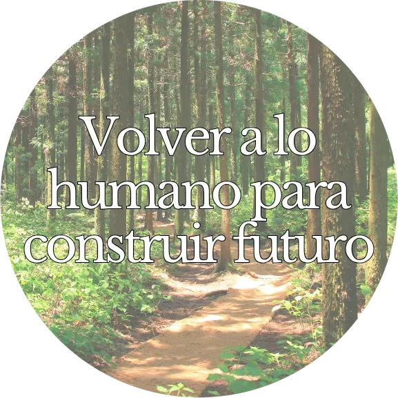 Camino entre árboles con el lema «Volver a lo humano para construir futuro»
