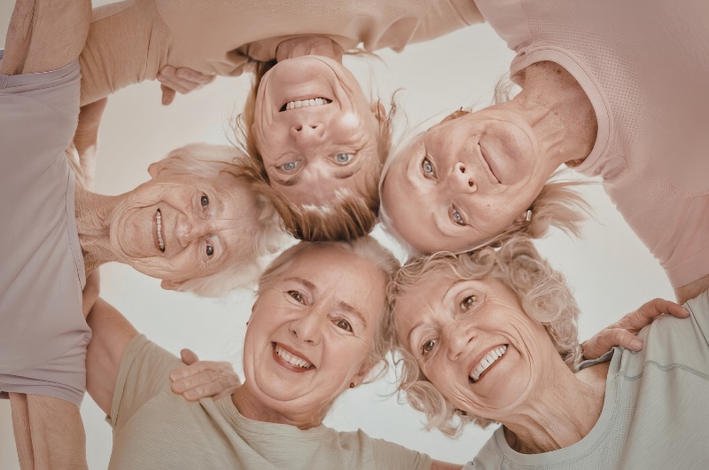 Grupo de mujeres mayores abrazadas y sonriendo en un programa de arte y bienestar