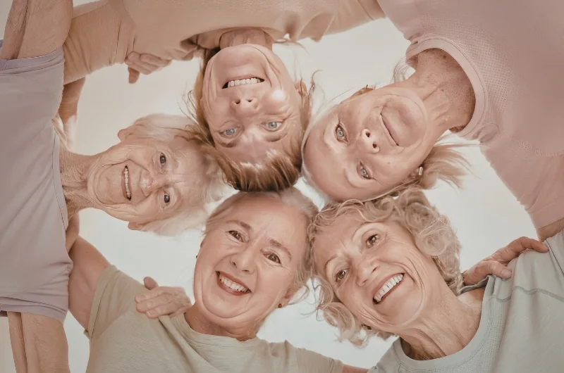 Grupo de mujeres abrazadas y sonriendo en un programa de arte y bienestar